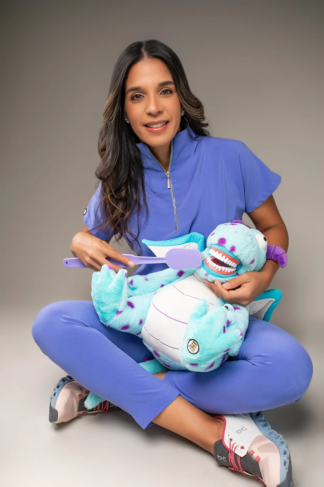 Dra. Alfonsina Cruz sonriente, con un muñeco didáctico para explicar el cuidado dental a los niños